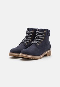 Botas de tobillo de ante azul marino con cordones grises, cuello acolchado y suela de goma marrón. Presenta detalle de costura y logo en el lateral.