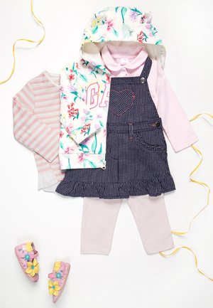 Vrstvený dětský outfit zahrnující květinovou mikinu, růžové triko s dlouhým rukávem, pruhovanou halenku, námořnické overal s kapsou ve tvaru srdce a růžové boty se žlutými květy.