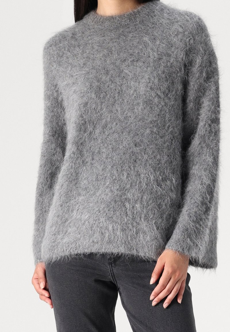 Grauer, flauschiger Pullover mit rundem Ausschnitt und langen Ärmeln. Aus weichem Material hergestellt, mit lockerer Passform, verfügt über einen Saum, der leicht geschwungen ist.