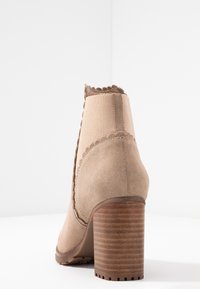 Vihreät mokkanahka ankle-kengät, joissa on ribbed ruskea korko, aaltoileva reuna ja pehmeät kangaspaneelit. Suunniteltu tiiviiseen istuvuuteen ja vakauteen.
