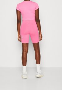 Rosa Croppad T-shirt och matchande hög midja shorts. Mjukt tyg, figursydd design. Shortsen har en stor vit kontur bokstäver detalj.