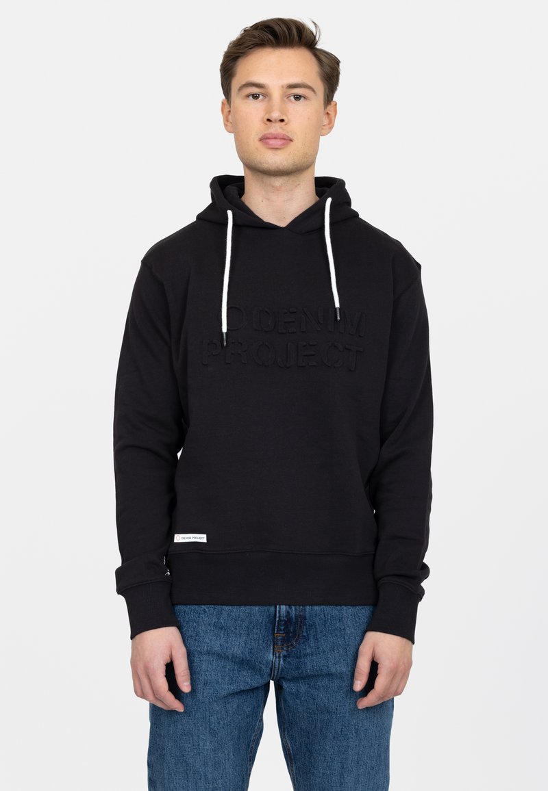Felpa nera con logo testurizzato, cordini regolabili e polsini a costine. Un paio di jeans blu visibili sotto. Design semplice e casual.