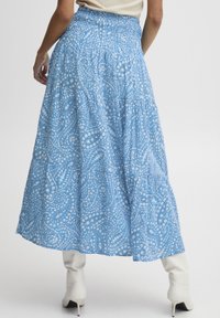 Fustă maxi cu model albastru, cu talie elastică, având un design floral și spiralat, realizată dintr-un material ușor, asortată cu cizme albe până la genunchi.