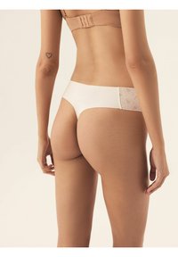 Białe hipsterskie majtki z koronkowymi detalami z tyłu, charakteryzujące się gładką teksturą i minimalistycznym wzornictwem.