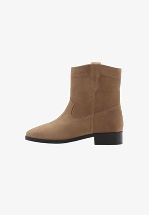 Stivale alla caviglia in suede marrone con punta arrotondata, tacco basso a blocco e dettagli di cucitura laterale. Presenta una linguetta sul retro per una facile calzata.