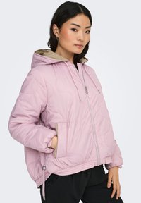 Vaaleanpunainen toppatakki, jossa on beige huppu, edessä vetoketju, kiristysnauhalla säädettävä helma ja joustavat hihansuut.