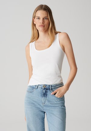 Top bianco senza maniche con scollo quadrato, realizzato in un morbido misto cotone, abbinato a jeans in denim azzurro chiaro con chiusura a bottone.