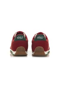 Sneaker rosse con upper in suede e mesh, dettagli bianchi e verdi, suola in gomma testurizzata e "1967" stampato sul tallone.