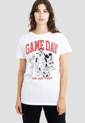 Young woman wearing a white T-shirt with "GAME DAY" in red and Disney characters Mickey, Goofy, and Donald dressed in soccer gear.