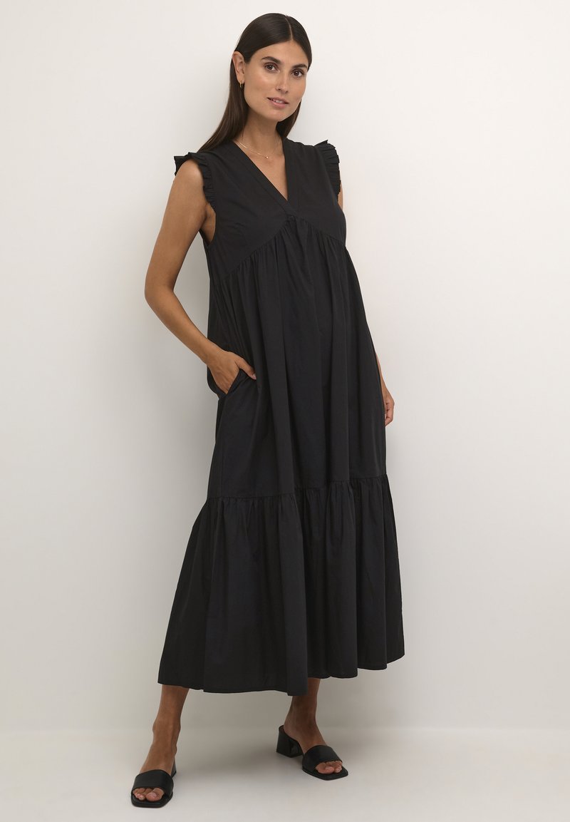 Black sleeveless maxi dress with ruffled shoulder accents, V-neck, and gathered tiers, featuring side pockets and a flowy silhouette.