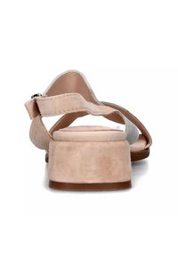 Sandalo in suede beige con tacco a blocco medio, cinturino alla caviglia regolabile e suole lisce. Presenta un design minimalista e una texture morbida.