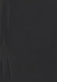 Tecido preto com uma textura suave, apresentando fendas laterais para um movimento adicional e um design elegante e simples. Sem padrões ou acentos adicionais.