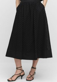 Jupe midi noire avec un design à oeillets, dotée d'une taille froncée, de poches latérales et d'un ourlet uni. Fabriquée en tissu léger et texturé.