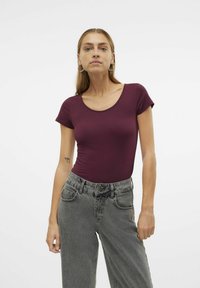 Body bordeaux à manches courtes avec un décolleté arrondi, associé à un jean en denim gris taille haute, doté de poches avant et d'une coupe décontractée.