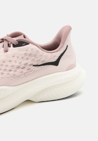 Ljusrosa träningsskor med en strukturerad ovandel, svarta accenter och vit dämpad sula. Har snörningssystem och rundad klack.