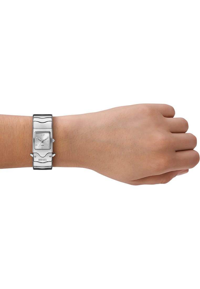 Silberne rechteckige Uhr mit einem Metallarmband am Handgelenk. Die Uhr hat ein weißes Zifferblatt, eine glatte Textur und eine auffällige 'DIESEL'-Markierung.