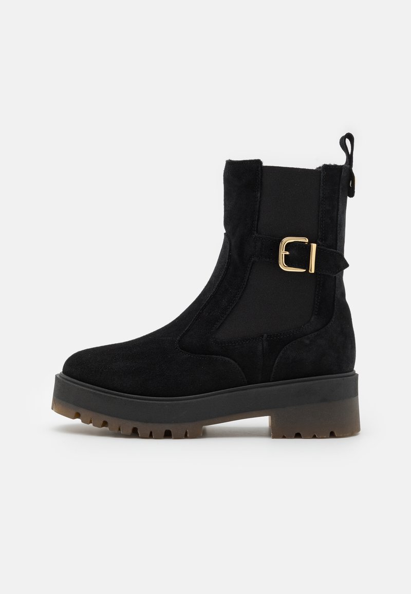 Bottines noires avec un dessus en daim, des panneaux latéraux élastiques, un détail de boucle dorée et une semelle en caoutchouc épaisse à crans pour une meilleure adhérence.