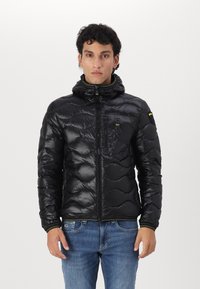 Giubbotto invernale nero con design trapuntato, cappuccio e chiusura con zip. Presenta una tasca sul petto e dettagli verdi lungo il colletto e i polsini.