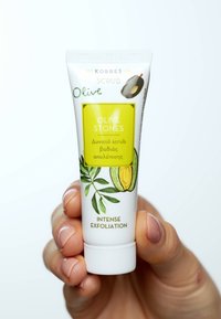 Korres skrubb i en vit 50 ml-tub. Har en grön och gul etikett med illustrationer av olivkärnor. Texten säger "Intensiv Exfoliering."