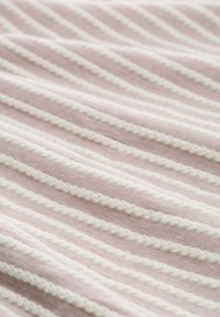 Textil med ljusrosa och vita ränder. Texturen har en ribbad yta med vågiga vita accentlinjer som löper diagonalt.