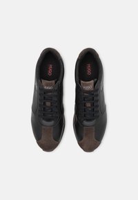 Baskets en cuir noir et daim marron avec un design à lacets. Comprend des semelles intérieures de marque et des panneaux contrastants au niveau des orteils et des côtés.