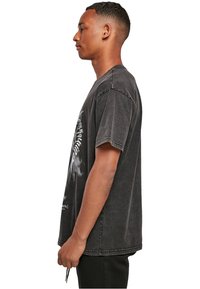 Sort oversized t-shirt med en falmet overflade og korte ærmer, der har et grafisk print på forsiden og en rund halsudskæring.