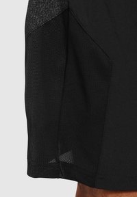 Svart atletisk tröja med ett strukturerat meshpanel på sidan, slätt tyg och en något böjd nederkant för förbättrad rörlighet.