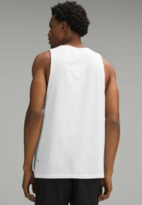 Hvid ærmeløs tanktop lavet af bomuld, med rund hals og en afslappet pasform. Sideudskæring og kanten detaljer synlige. Sorte shorts er iført.