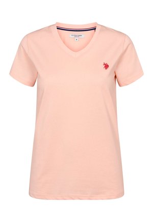 Svetlo roza bombažna majica z v-izrezom, kratkimi rokavi in majhnim rdečim vezenim logotipom na levi strani prsi.