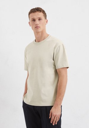 Light beige cotton t-shirt with short sleeves, a round neckline, and a relaxed fit. Smooth texture, no visible patterns or accents.