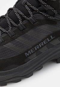 Czarne buty trekkingowe wykonane z siateczki i zamszu, z teksturowaną cholewką, odblaskowymi sznurowadłami oraz uformowaną podeszwą z wzorami zapewniającymi przyczepność.