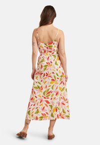 Blumenkleid im Maxistil mit dünnen Trägern, mit einem hellen Hintergrund und Mustern aus roten, rosa und grünen Blättern, tailliert.