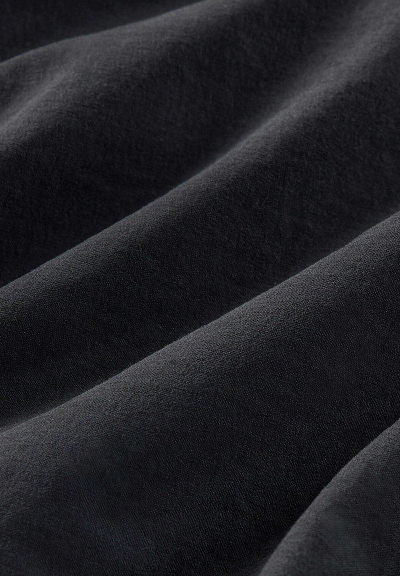 Tela negra con una textura suave, que muestra pliegues y ondas sutiles, destacando su suavidad y ligero brillo.
