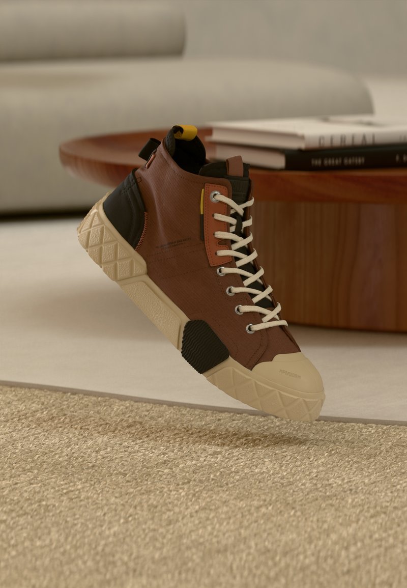 Αθλητικό παπούτσι τύπου μποτάκι κατασκευασμένο από καφέ ύφασμα με μαύρες λεπτομέρειες και λευκά κορδόνια. Διαθέτει ανάγλυφη σόλα και κίτρινη θηλιά τράβηγματος. Γεωμετρικά σχέδια.