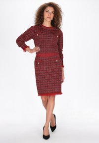 Piros tweed két részes öltözet, texturált, kockás mintával. A felső hosszú ujjú és kerek nyakú. A szoknya fránk részletekkel rendelkezik.