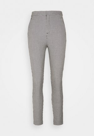 Pantalon slim taille haute avec un petit motif à carreaux noir et blanc et des poches avant sur fond blanc.