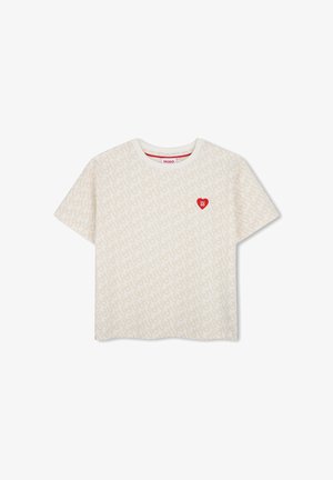 T-shirt blanc à manches courtes avec un motif de logo beige subtil sur toute la surface et un petit emblème en forme de cœur rouge avec texte sur la poitrine gauche.