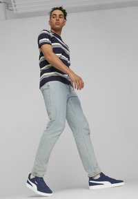 Marine- og hvide stribede t-shirt, lyseblå jeans og marinesko med hvide accenter. Glat stof, afslappet pasform og bukser til anklen.