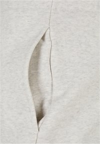 Ljust grå sweatshirtmaterial som visar en sidficka. Mjuk textur med ett subtilt, blandat mönster. Rak skärning.