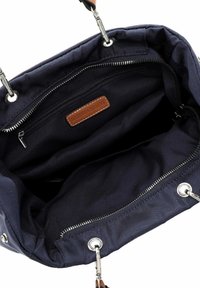 Sac à main bleu marine avec fermetures éclair et attaches argentées, montrant les compartiments intérieurs et une étiquette de marque en cuir marron.