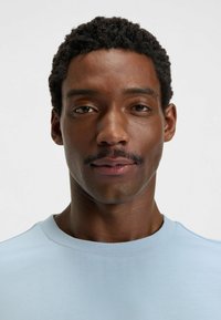 Light blue crew-neck t-shirt made of cotton blend fabric, smooth texture, fitted design, featuring a simple, clean silhouette.