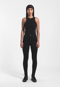 Černý bezrukávový top spárovaný s černými skinny džíny s vysokým pasem. Doplněno čelenkou a černými teniskami s hladkou texturou.