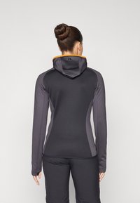 Hooded athletic jacket in black with grey accents, made of stretchy fabric; features an orange interior hood and fitted design.