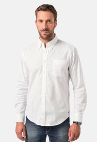 Witte longsleeve shirt met knoopsluiting op de kraag, één borstzak en een gebogen zoom, gemaakt van een gladde stof. Draagt met blauwe jeans.