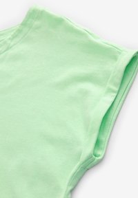 T-shirt in cotone verde chiaro con maniche corte arrotolate, caratterizzata da una texture morbida e un design semplice e privo di decorazioni.