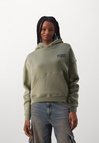 Felpa verde oliva, materiale in cotone, vestibilità rilassata, tasca frontale, polsini e orlo a coste, stampato in nero "PEQUS" sul petto.