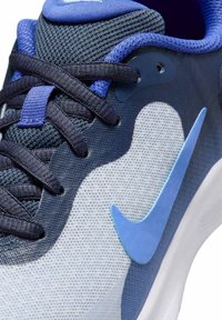 Zapatilla deportiva de malla en degradado de azules, con un diseño de ola blanca suave. Incluye cordones oscuros y un destacado acento de logo azul.