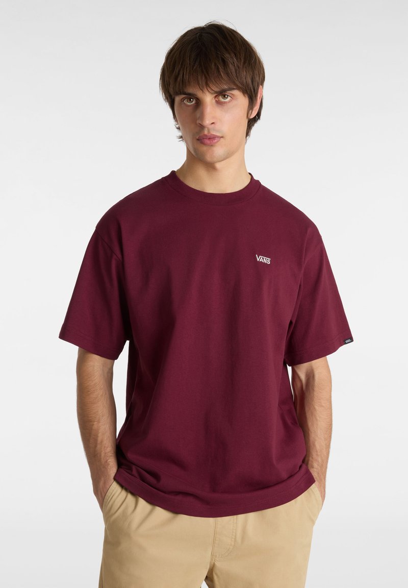T-shirt en coton bordeaux avec un col rond et des manches courtes, arborant un petit logo "VANS" blanc sur la poitrine. Texture lisse, coupe décontractée.