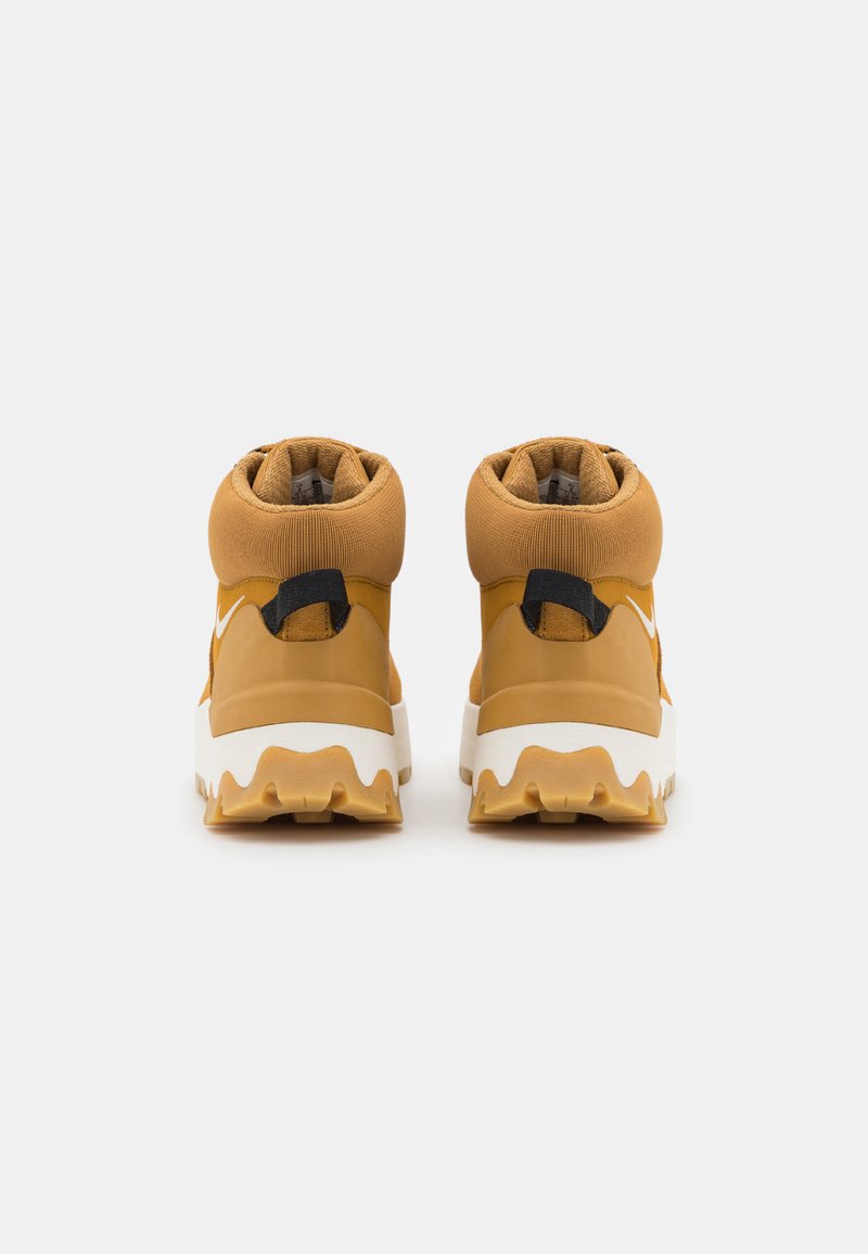 Hoge sneakers in mosterdgeel met een gestructureerde oppervlakte, witte middenzool en robuuste griploop. Voorzien van een zwarte hiel lus.