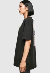 Sort oversized bomulds T-shirt med grafisk print på ryggen og korte ærmer. Lige kant og afslappet pasform.